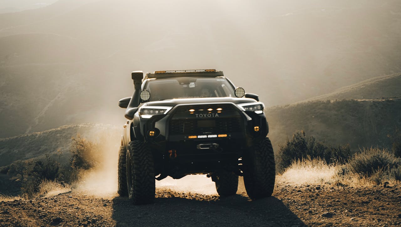 A rugged Toyota off-roading through a dusty mountain landscape at daytime.
